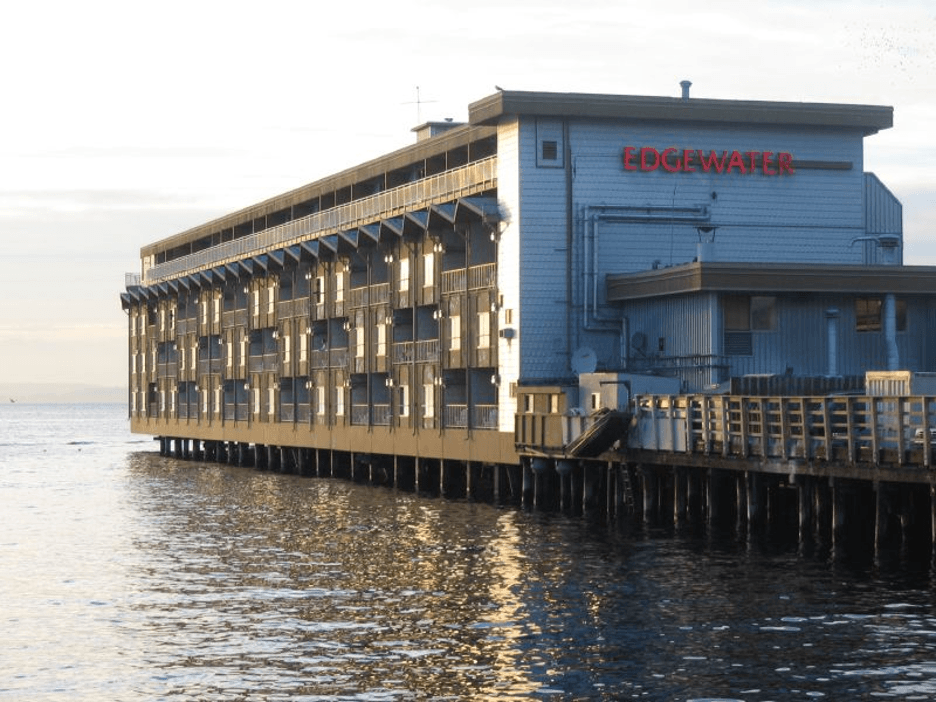 The exterior of the Edgewater hotel, sitting on a pier, with water in the foreground